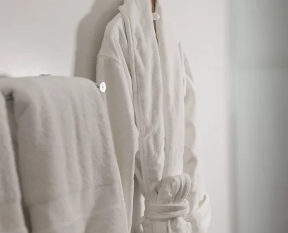 White bathrobes hanging on wall hooks in a minimalist bathroom or wardrobe scene.