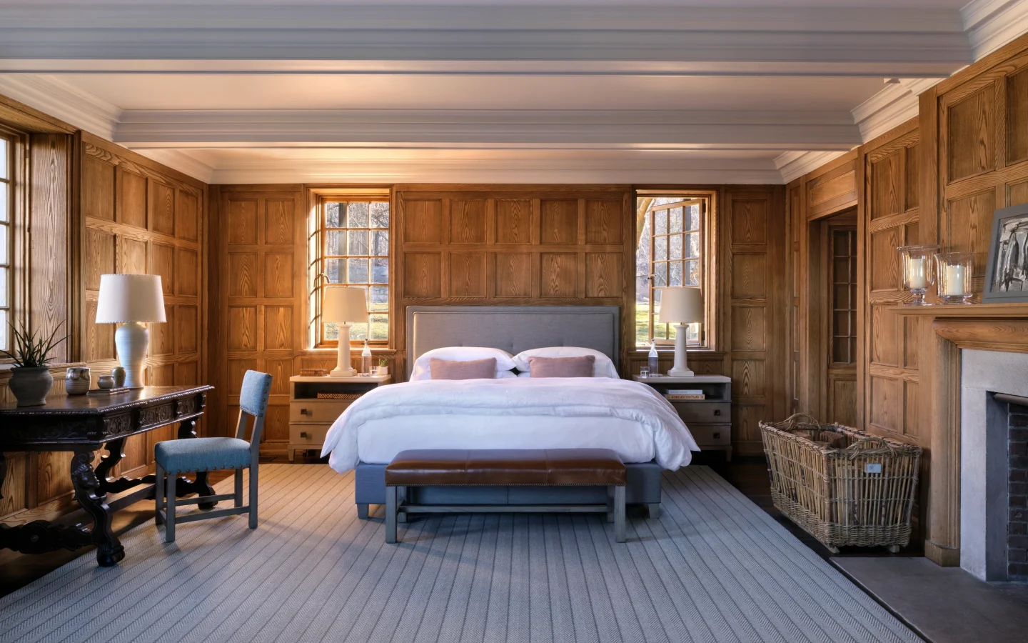 Warm, traditional bedroom with dark wood paneling, two beds, and natural light from windows.