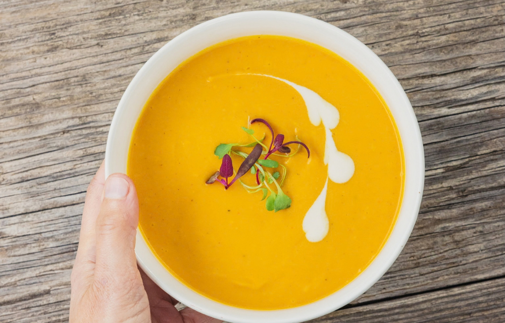 A white bowl of carrot ginger soup in fall at The Ranch Hudson Valley.