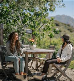 two girls sitting at table outside 