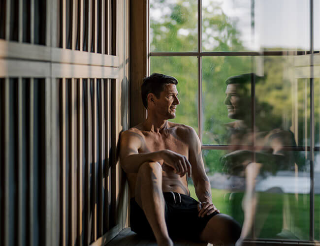 Man sitting in a sauna with an outdoor view