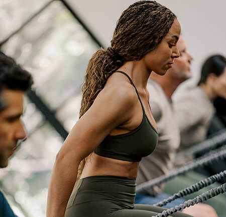 Woman working out in a group class pulling tension cords