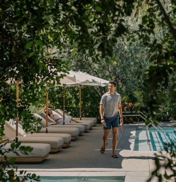Man walking by pool with lounge chairs